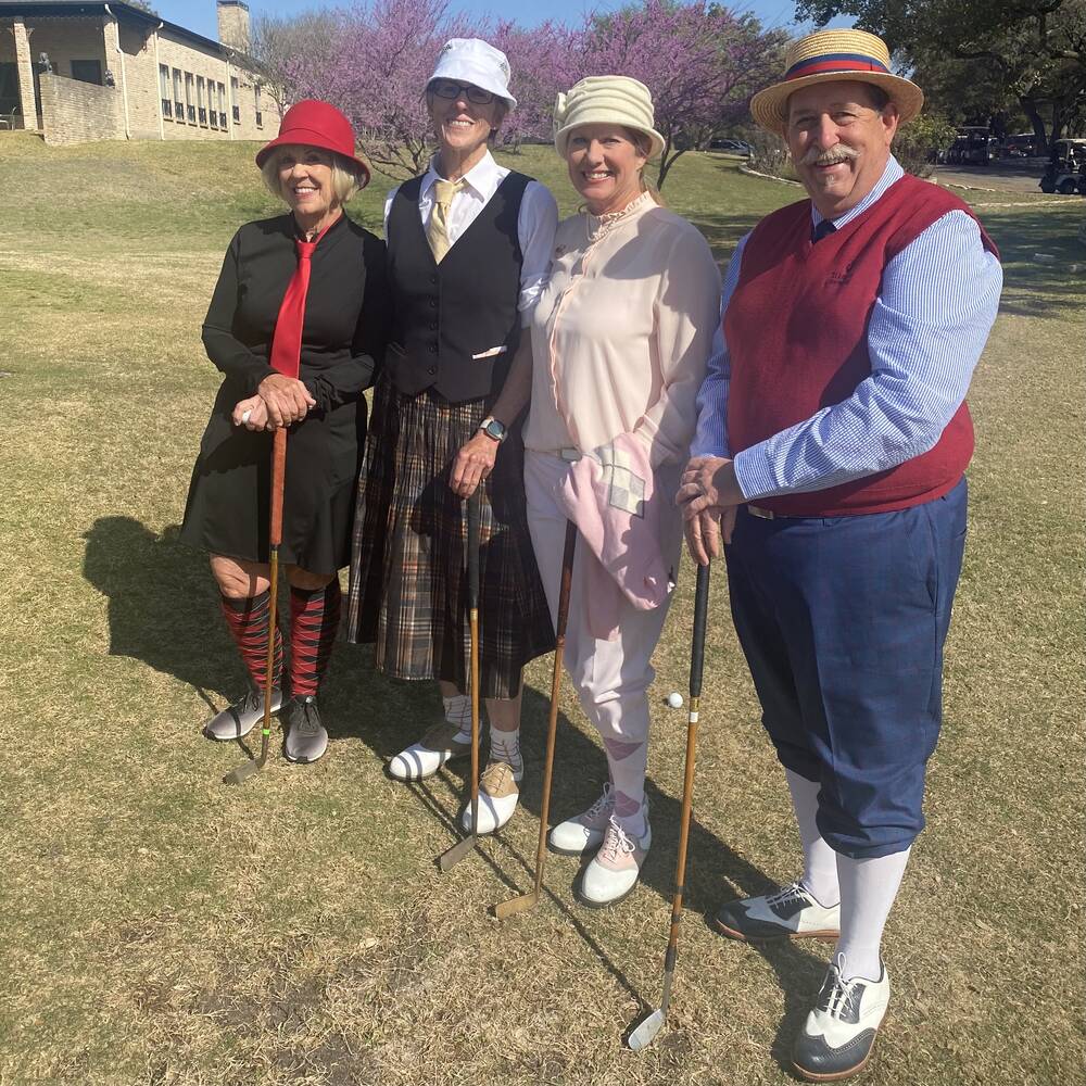 A foursome in period attire &mdash; cloche hats, red tie, and plaid skirt &mdash; posing with hickory-shafted clubs on the course